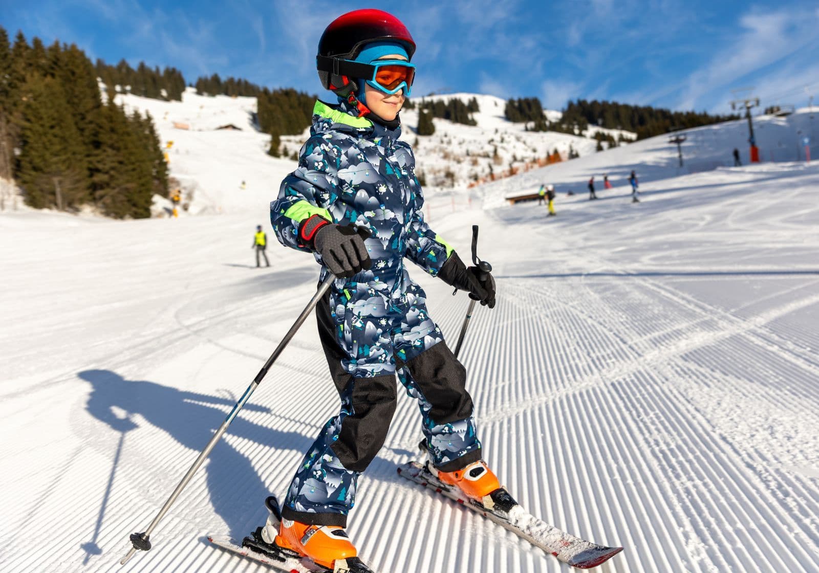 Barn iført flyverdragt og skiudstyr på ski på en løjpe