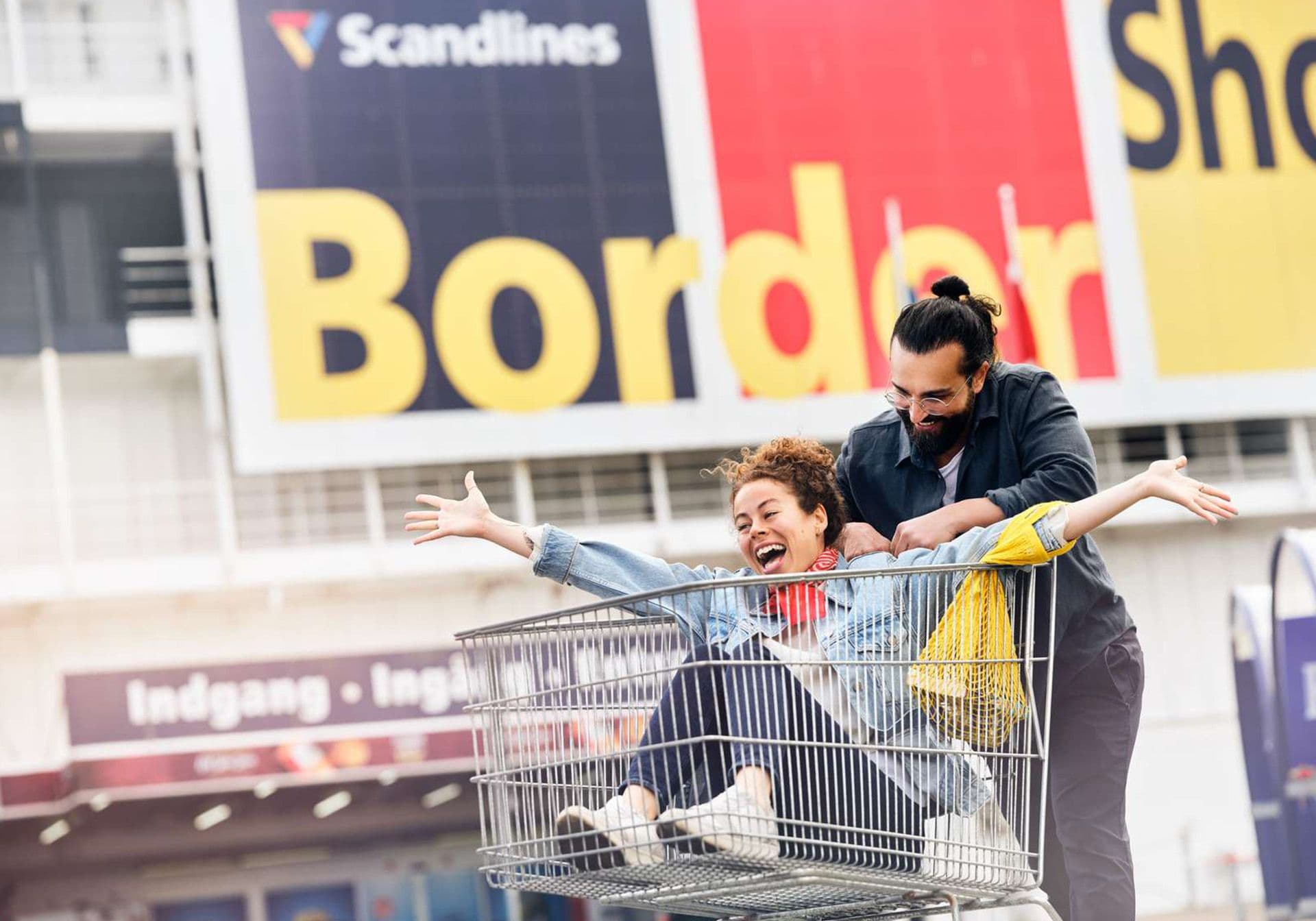 Happy woman in shopping cart outside BorderShop